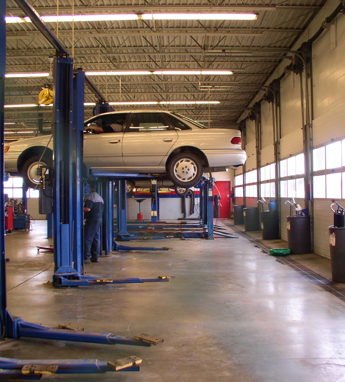 Car on hydraulic lift in auto repair shop.