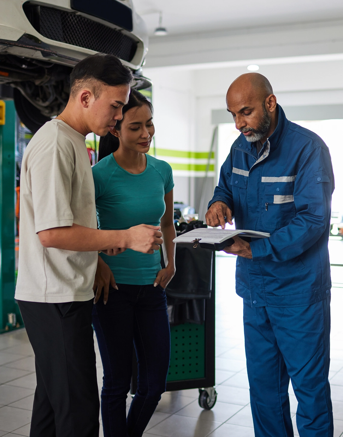 Mechanic explaining car details to two customers.