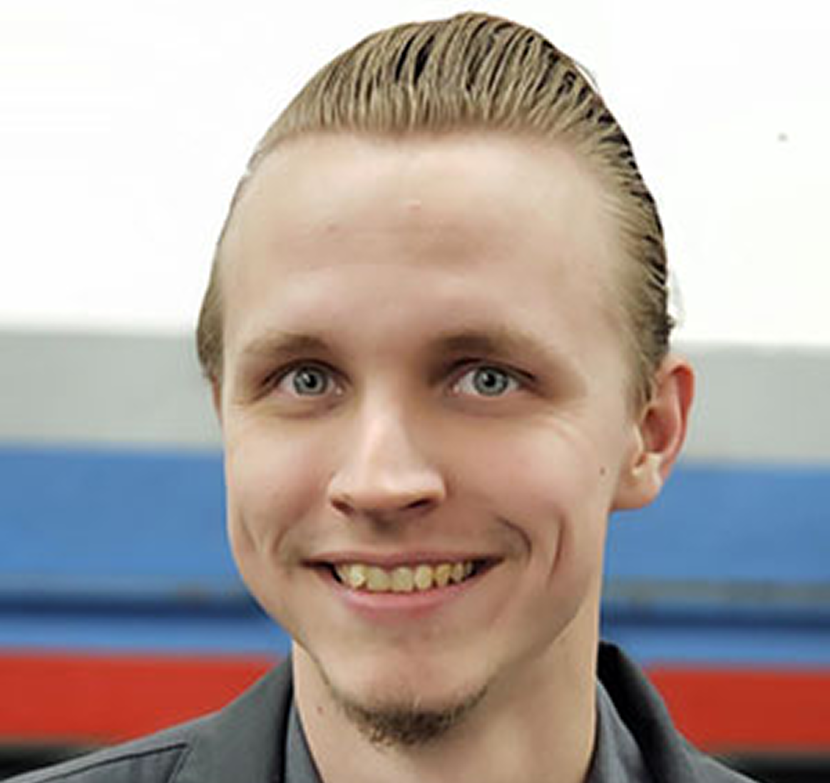 Smiling person with slicked-back hair.
