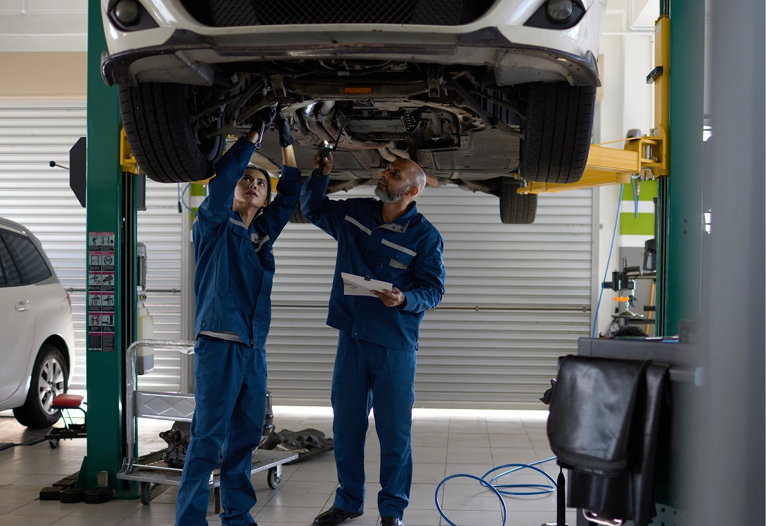 Mechanics inspecting car on hydraulic lift.