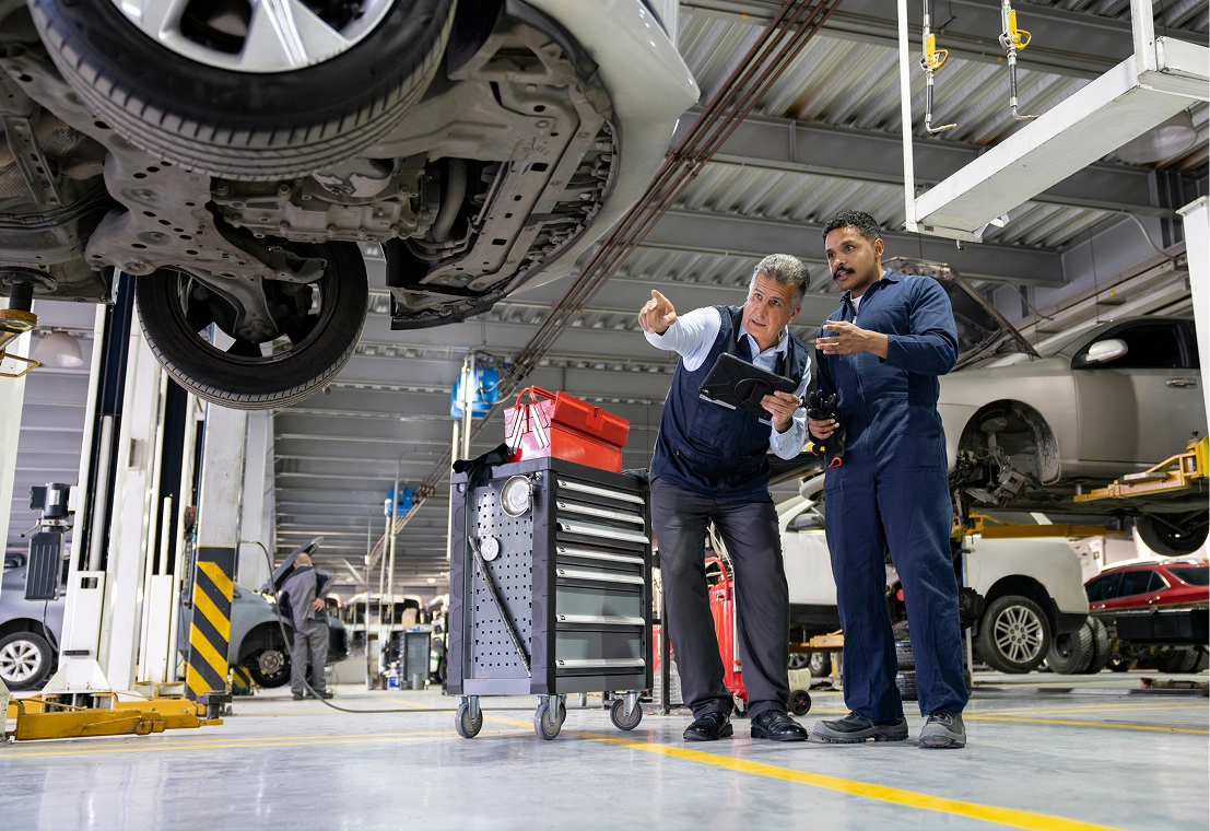 Mechanics inspecting vehicle in a garage.